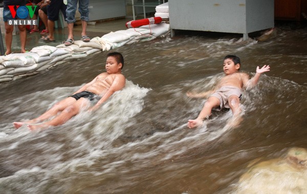 2 đứa trẻ chơi đùa với nước lụt tại đường Phahon Yothin